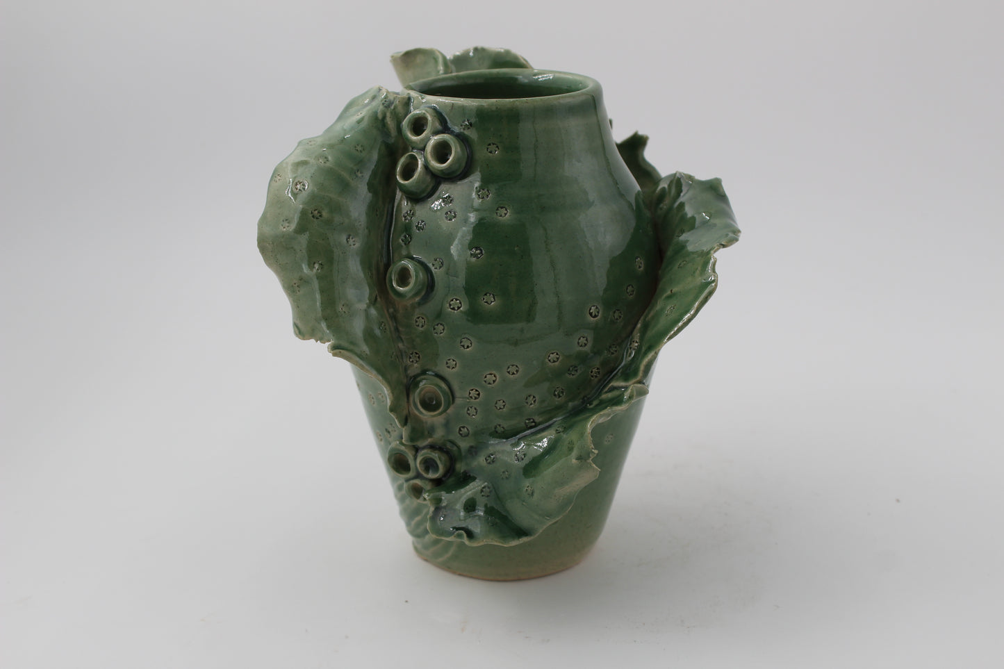 Green ceramic vase with textured surface on a white background