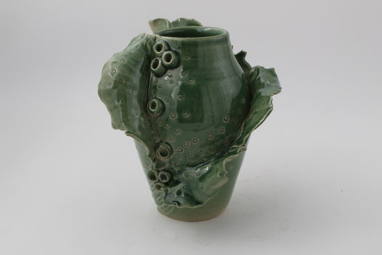 Green ceramic vase with textured surface on a white background
