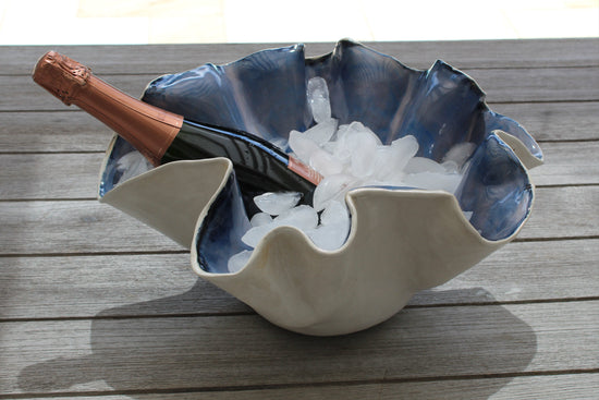 Shell-shaped ice bucket with a bottle of champagne on a wooden surface